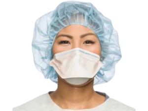 Healthcare worker wearing a white Halyard duckbill N95 respirator mask and light blue surgical bouffant cap against a black background.